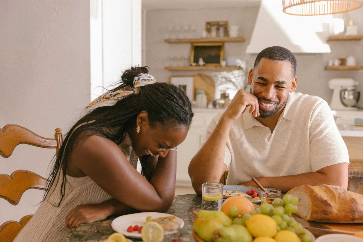 Mike Johnson laughing with a woman in a luxury kitchen, reflecting Oshun’s values of connection, joy, and natural beauty rituals.
