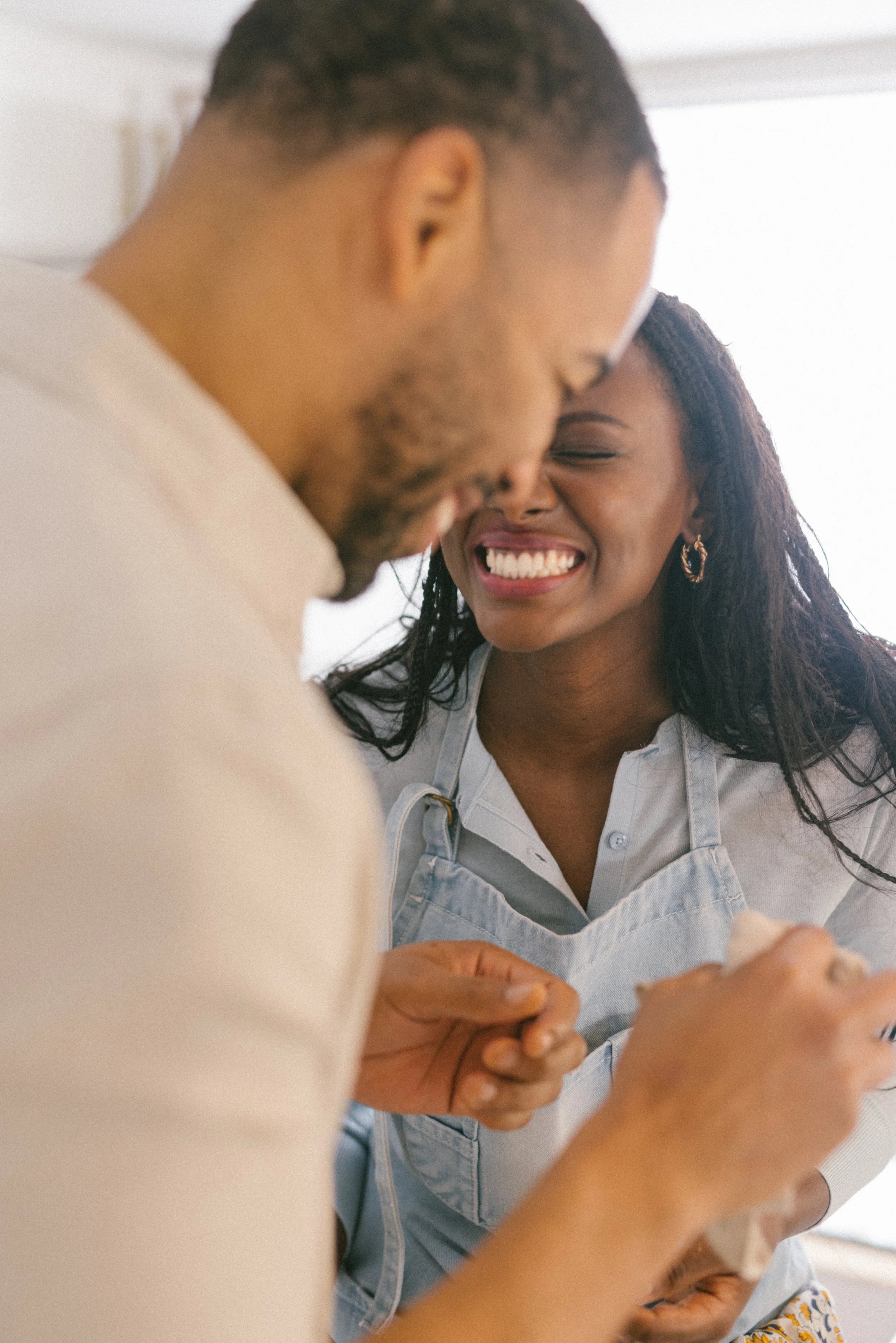 Two people in the kitchen, laughing together.