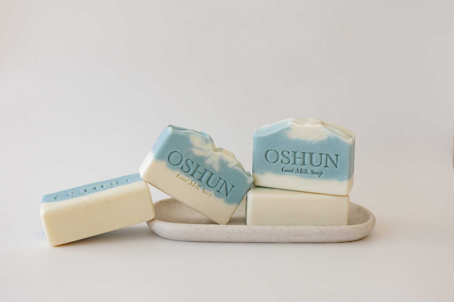 Three bars of Oshun soap on a white tray with a white background