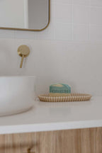 Bathroom setting with a soap dish holding a bar of soap labeled 'OSHUN' next to a sink.