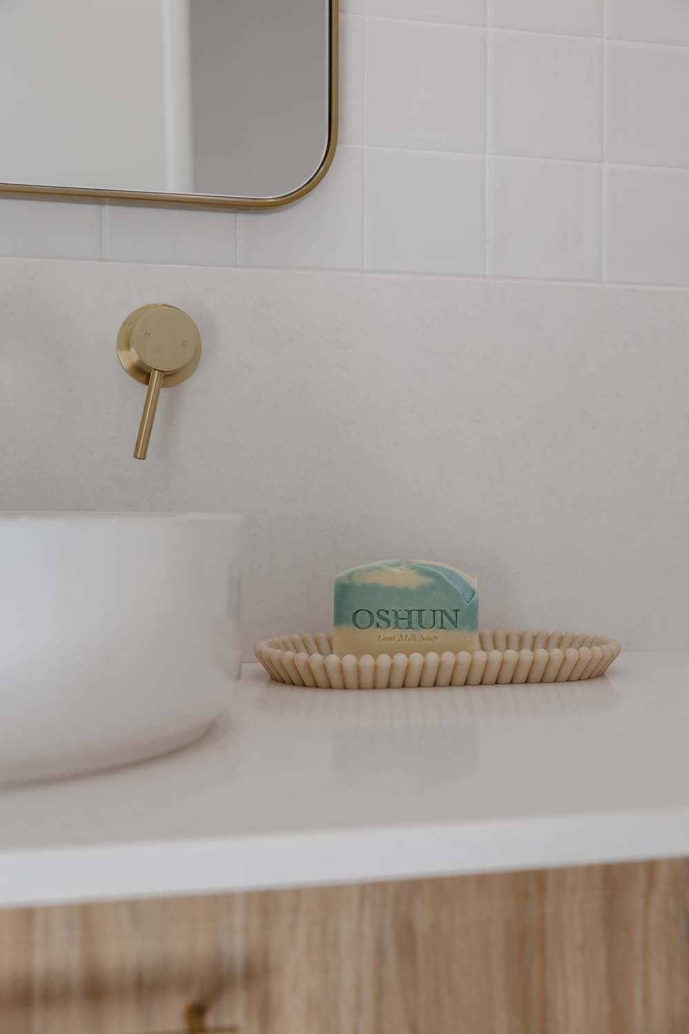 Bathroom setting with a soap dish holding a bar of soap labeled 'OSHUN' next to a sink.