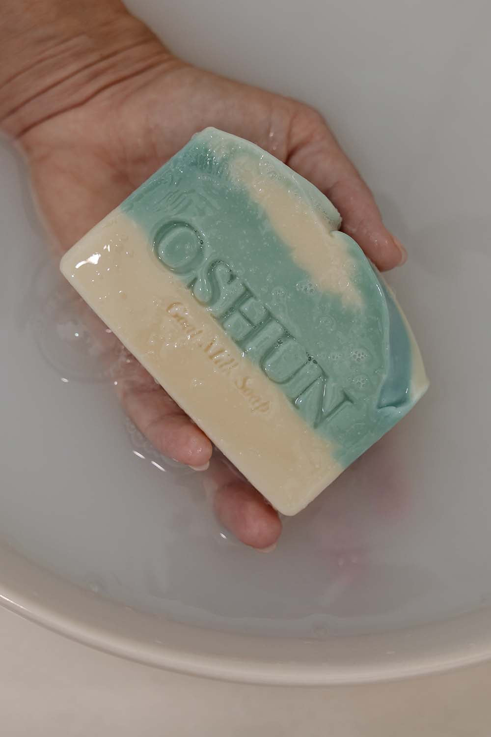 Hand holding a bar of Oshun soap