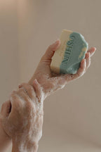 Hand holding a bar of soap with 'Oshun' branding
