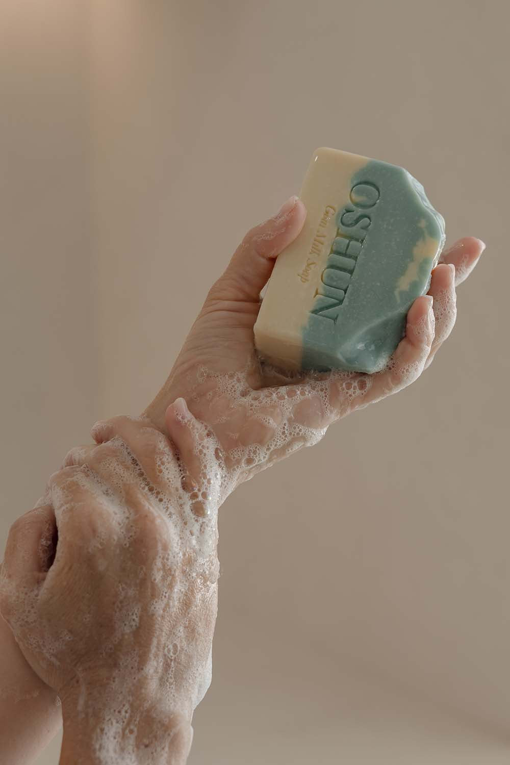 Hand holding a bar of soap with 'Oshun' branding