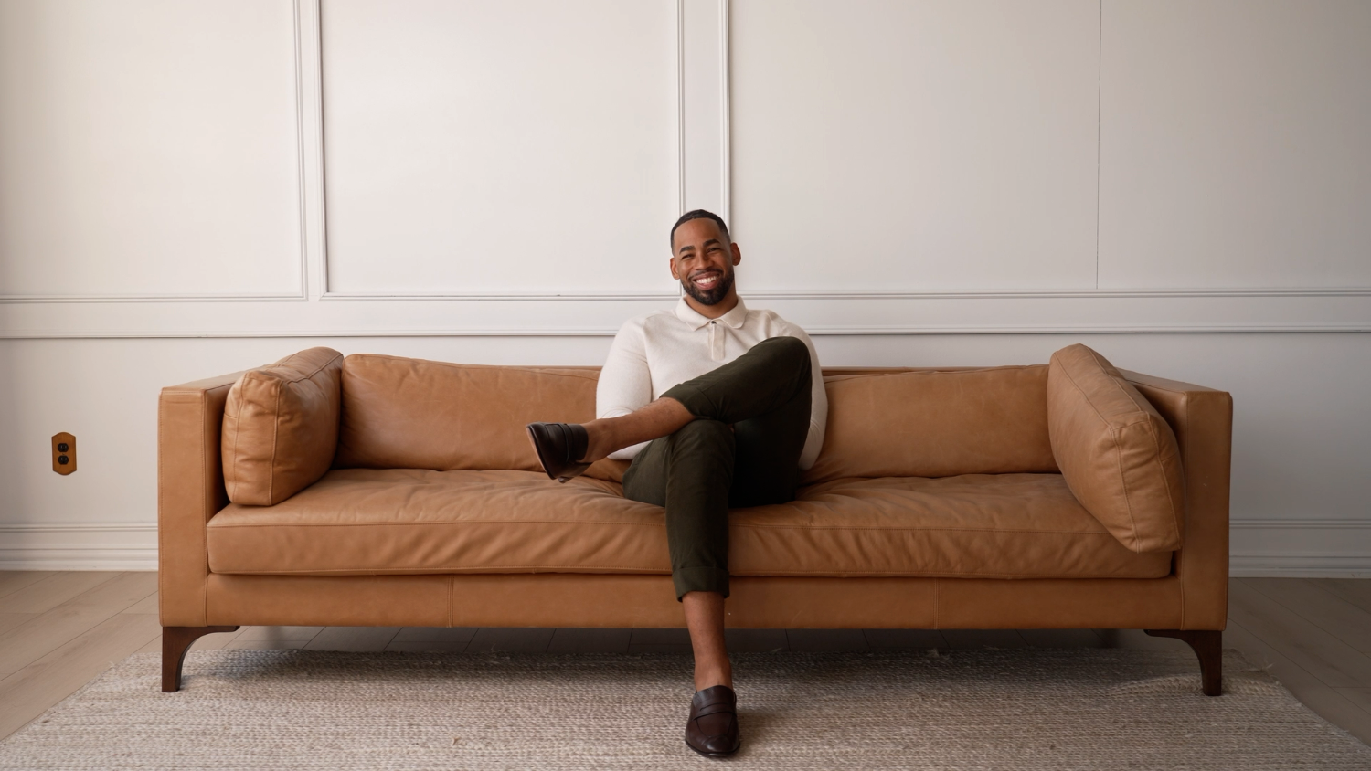 Mike Johnson, founder of Oshun Goat Milk Soap, smiling on a luxurious couch, representing the brand’s commitment to clean beauty and luxury skincare.