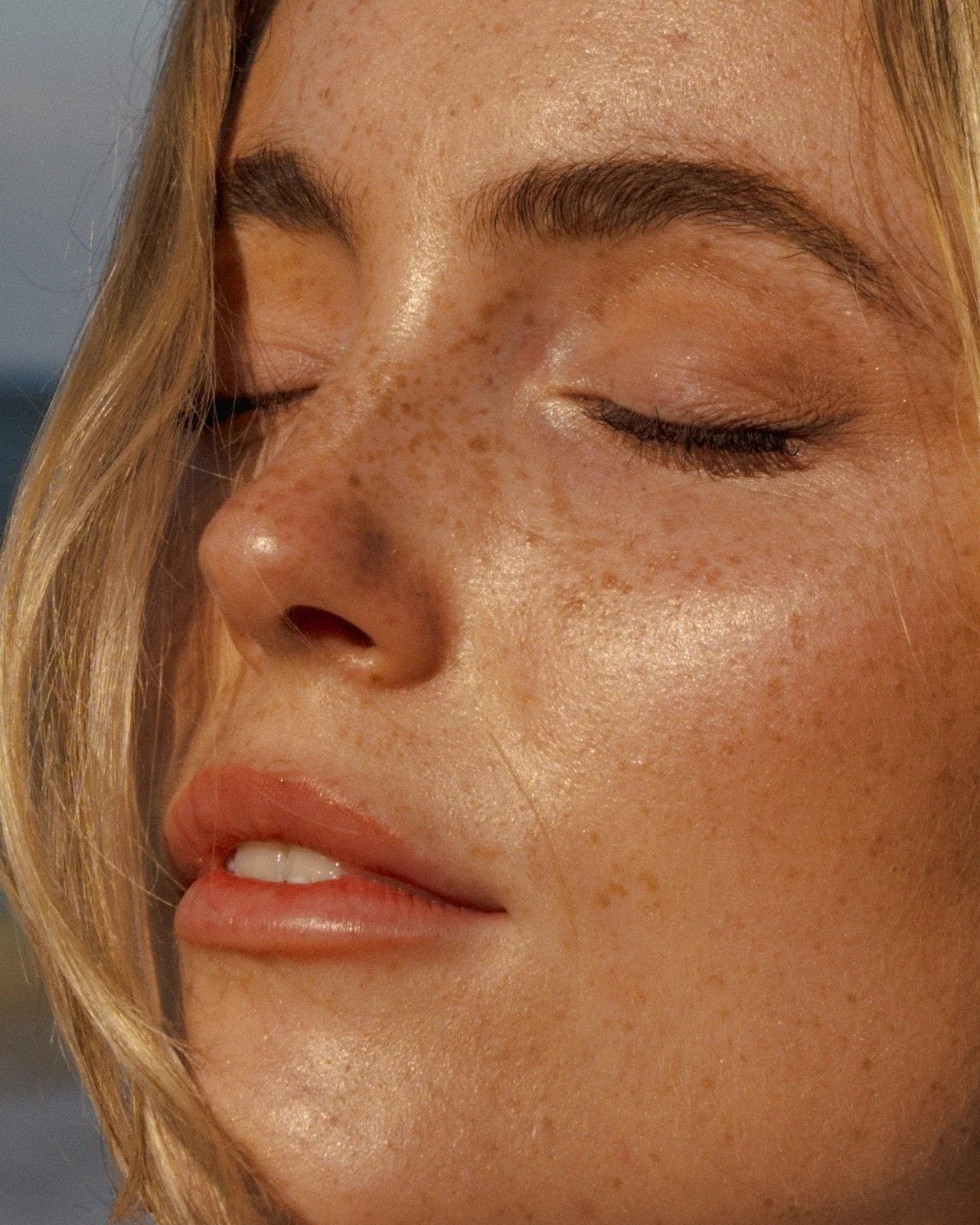 Close-up of freckled woman with radiant, calm skin—results of using Oshun goat milk soap for sensitive skin.