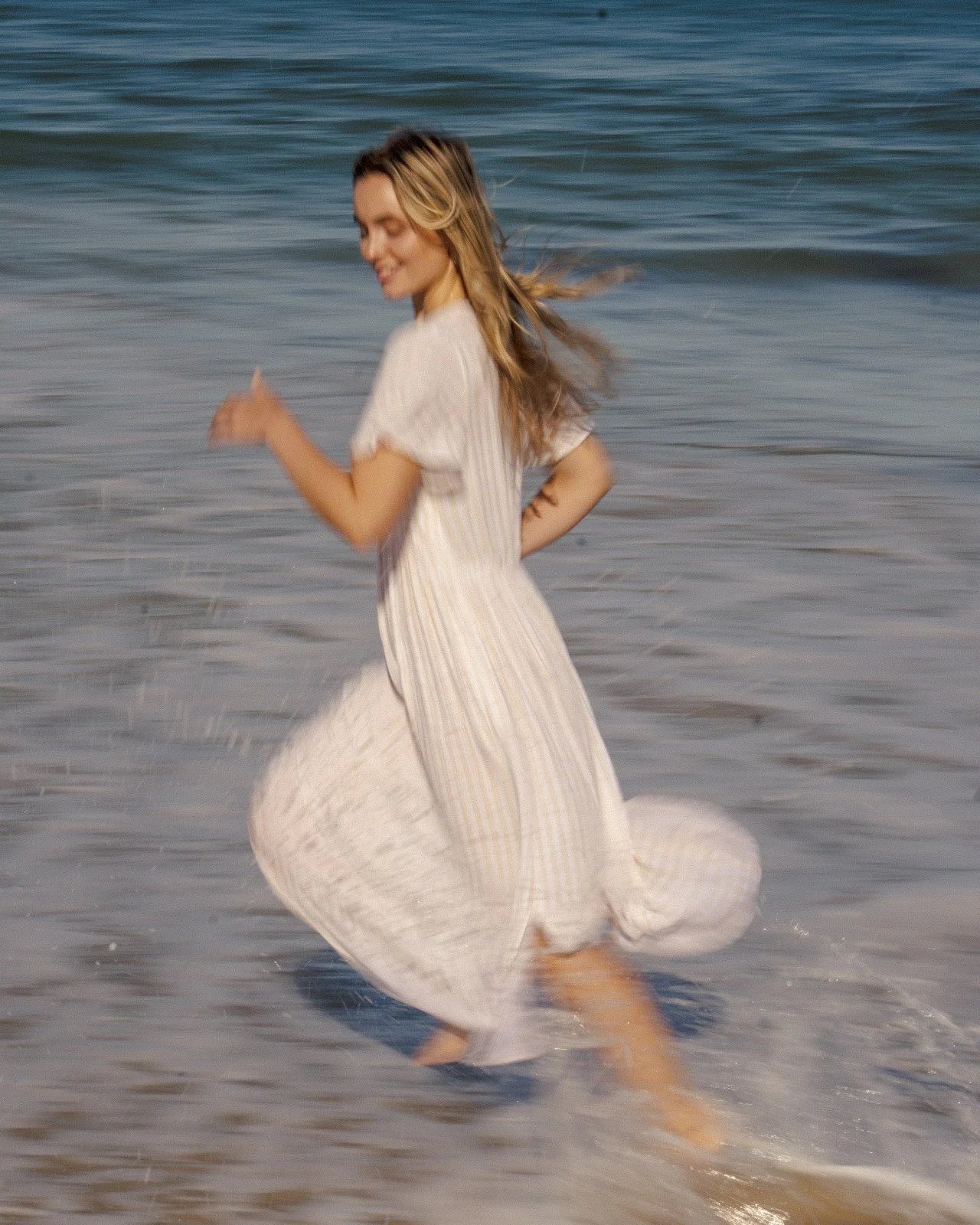 Blonde woman enjoying the ocean, celebrating natural beauty and the nourishing power of Oshun goat milk soap.
